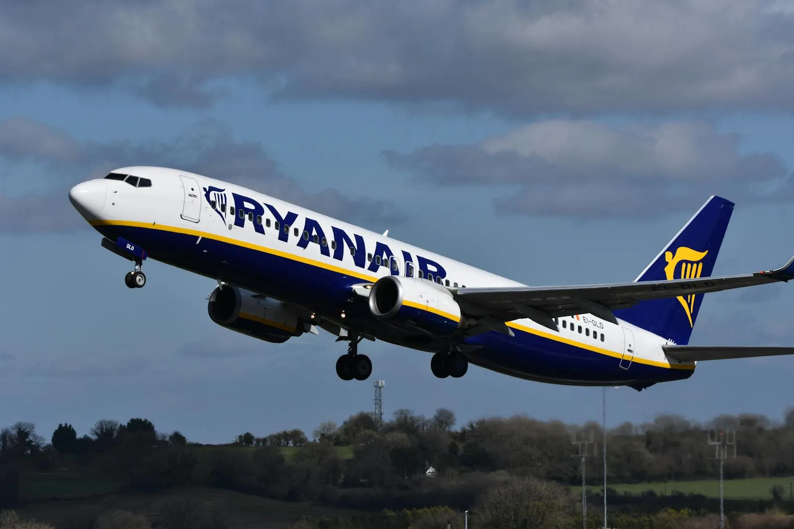A commercial Boeing 737 aircraft retracting its landing gear shortly after takeoff, photographed against a bright blue sky