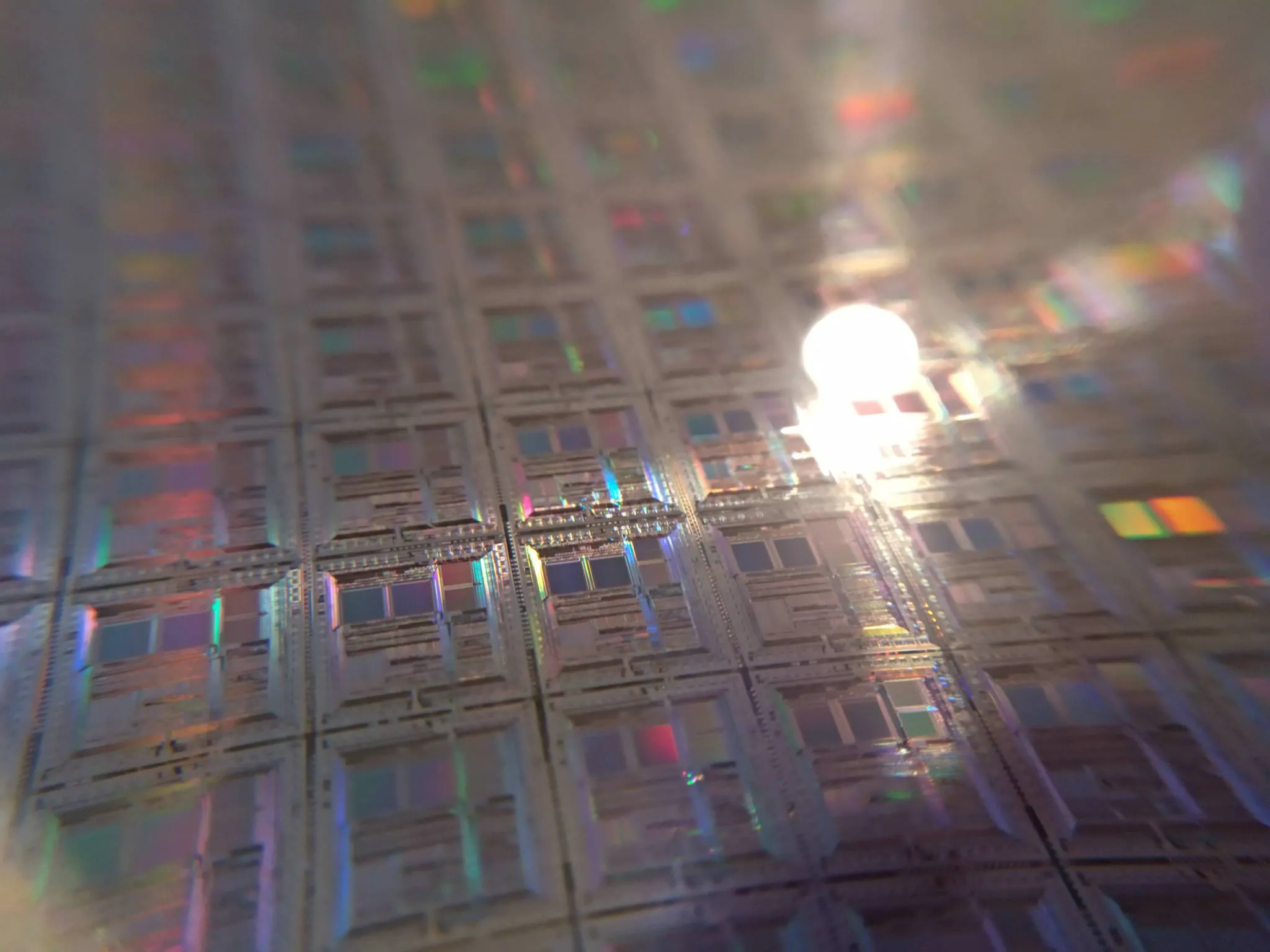 Close-up of a circular silicon semiconductor wafer reflecting light across its patterned surface