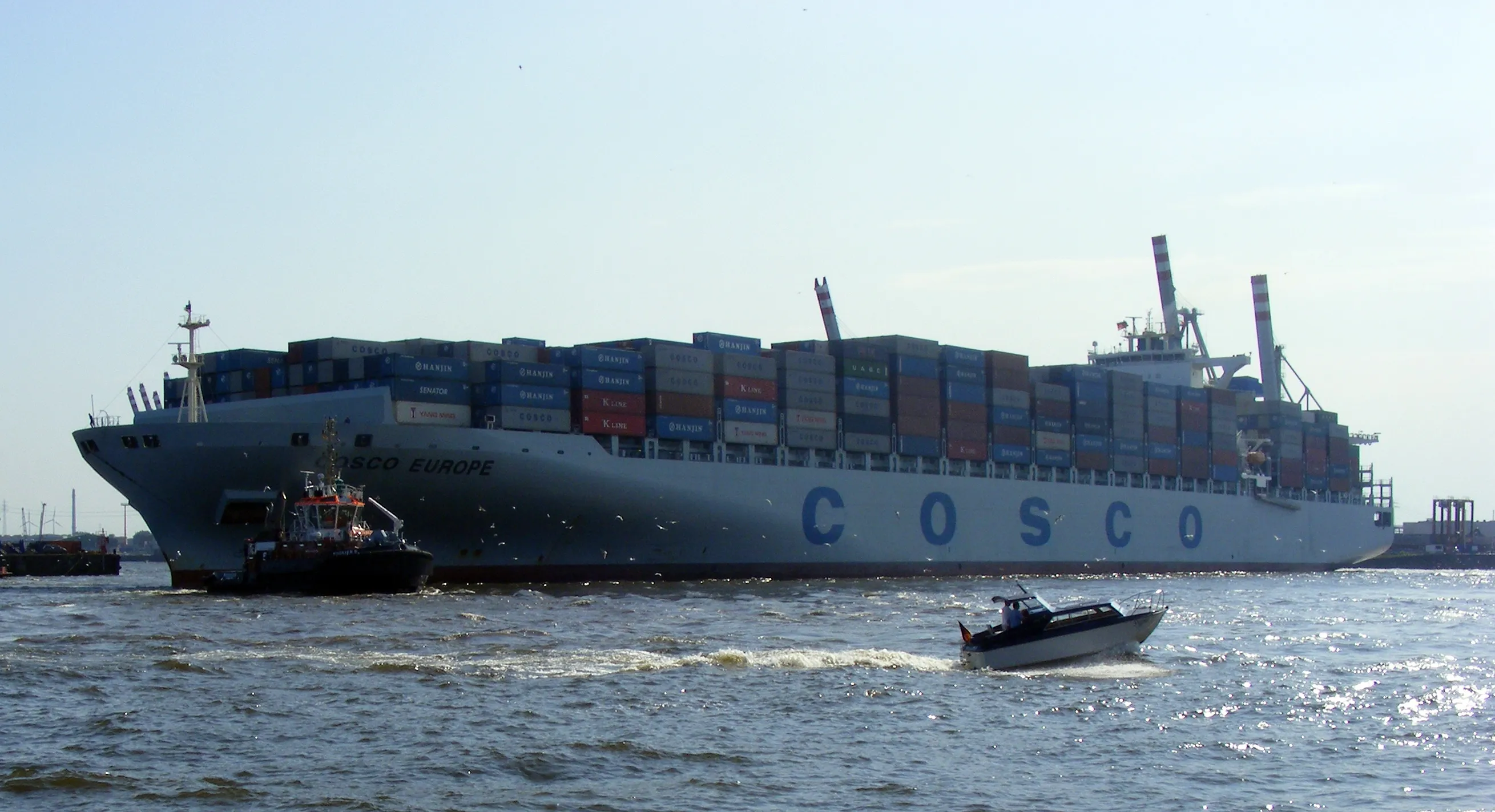 A large COSCO container ship named Europe, stacked with shipping containers, underway on open water.