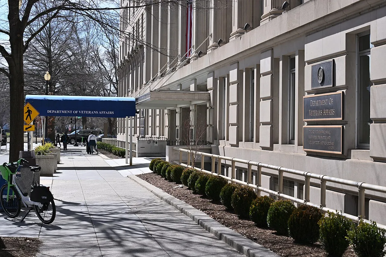 The Department of Veterans Affairs headquarters building on Vermont Avenue in Washington, D.C., a tall stone facade behind a perimeter fence.