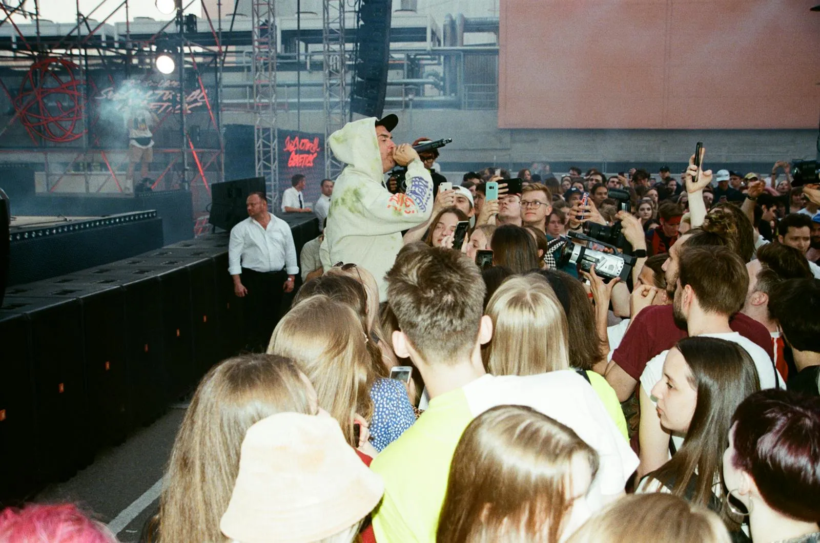 A packed indoor concert crowd facing an illuminated stage with performers and dramatic stage lighting