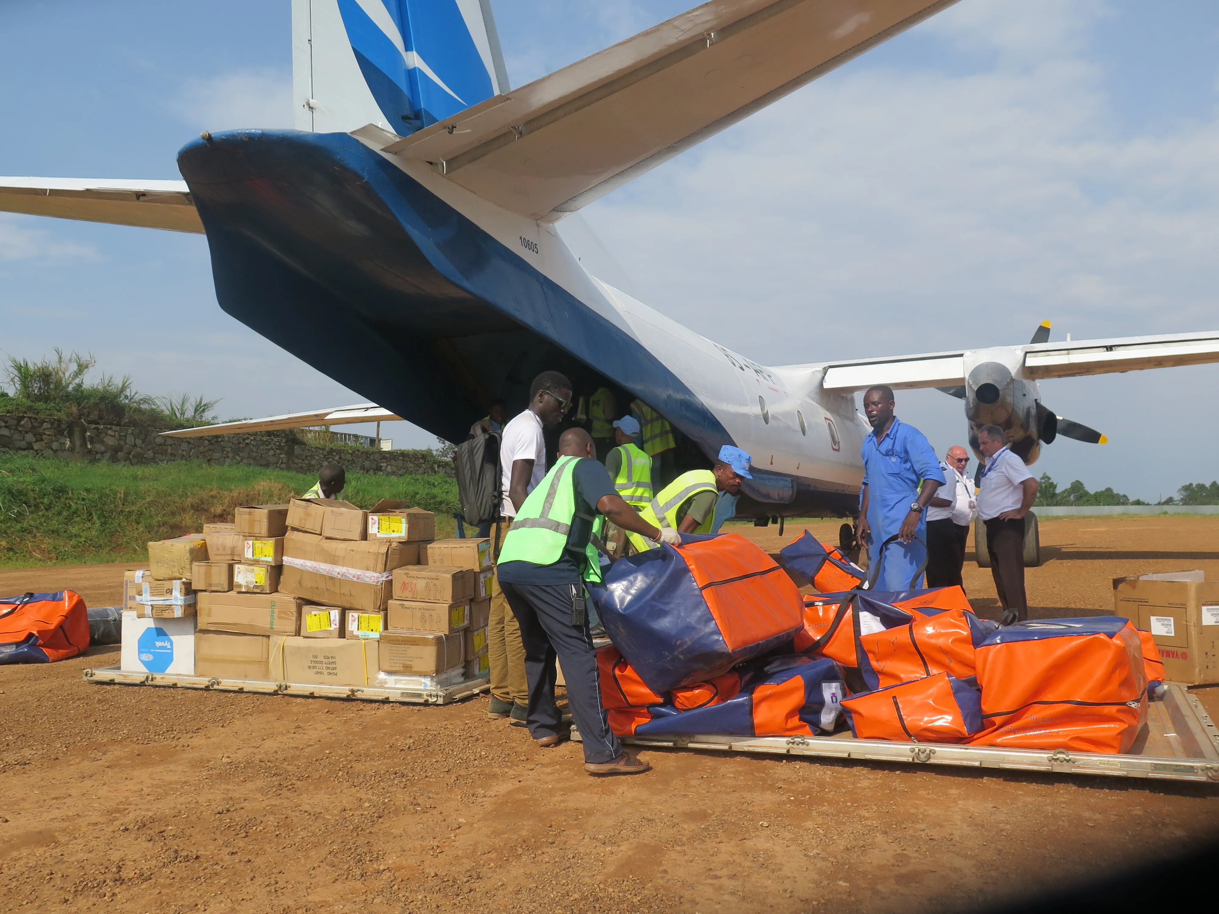 Health workers in blue vests unload medical supply crates from a vehicle at Beni Airport in eastern Congo during an Ebola response operation in North Kivu Province
