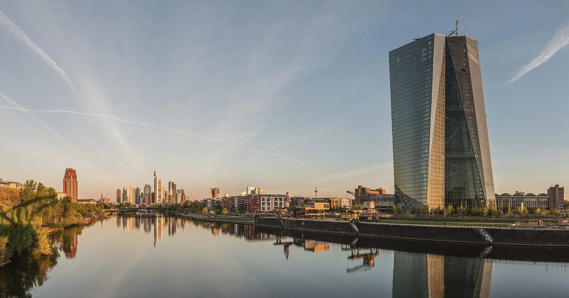 The twin-tower glass skyscraper of the European Central Bank rising above the Frankfurt skyline at dawn.