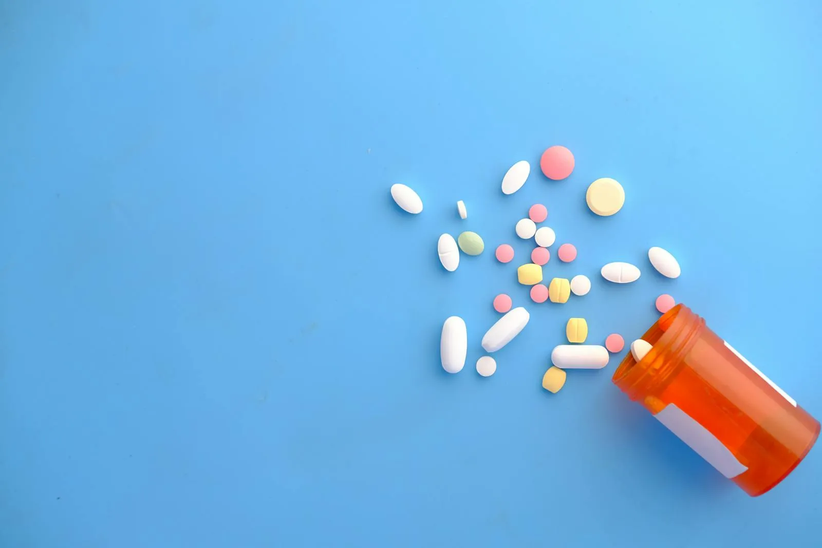 Prescription medication capsules and pills on a blue surface