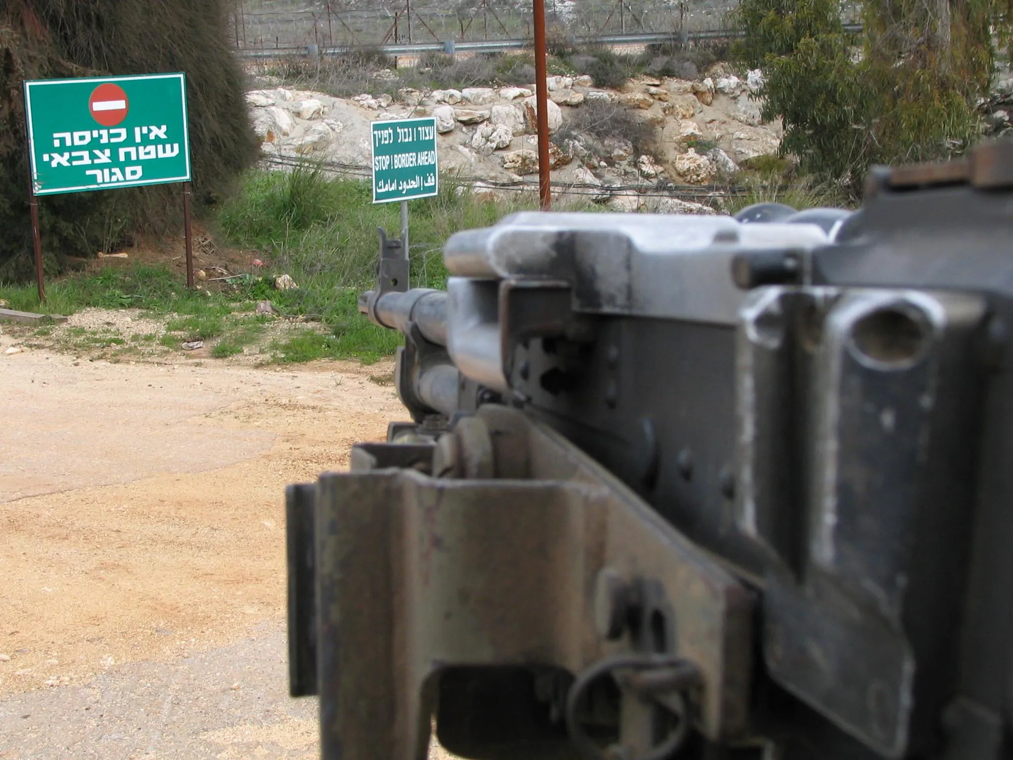 Israeli military warning signs at the Israel-Lebanon border reading 'Stop, border ahead' and 'No entrance, closed military area.'