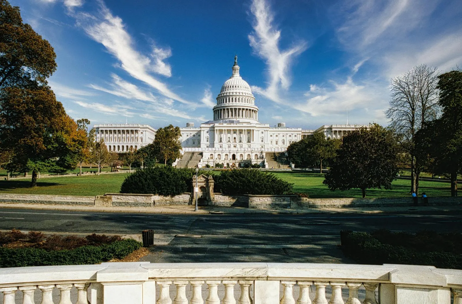 The United States Capitol Building rises on a clear day, showing the central dome and both legislative wings from ground level