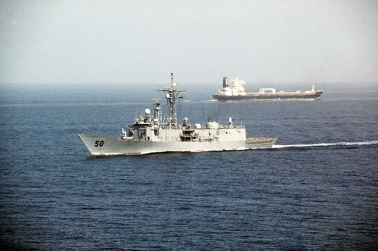 A U.S. Navy guided missile frigate passes an oil tanker in the Strait of Hormuz.