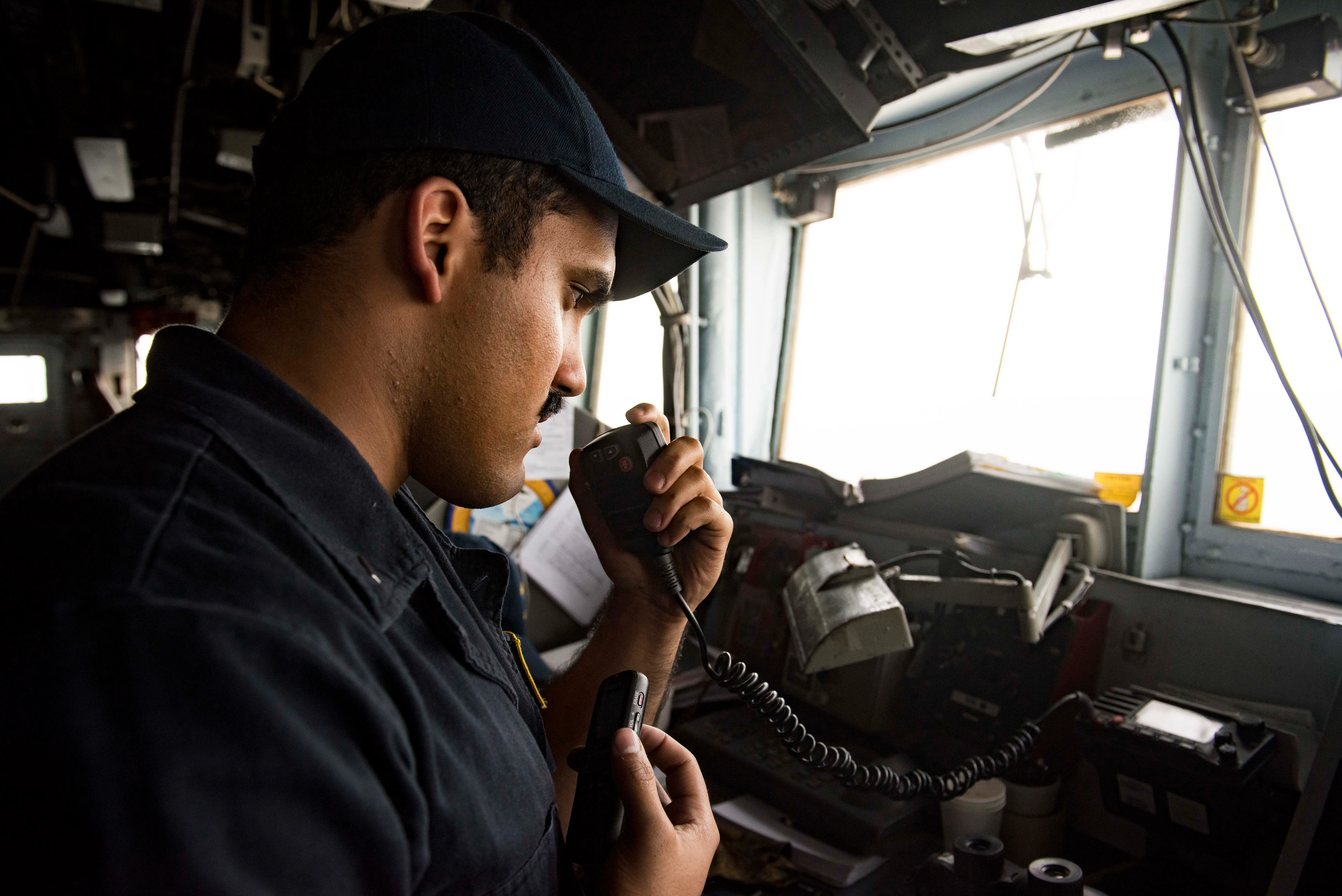 A U.S. Navy officer communicates over radio from the bridge wing of USS San Jacinto during a transit of the Strait of Hormuz