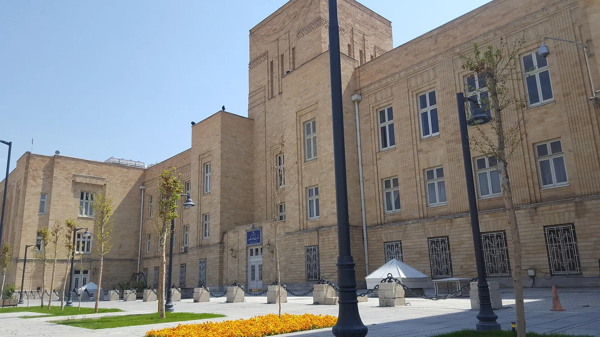 The Iran Ministry of Foreign Affairs building in Tehran, a multi-story modernist structure behind iron gates, photographed from street level on a clear day