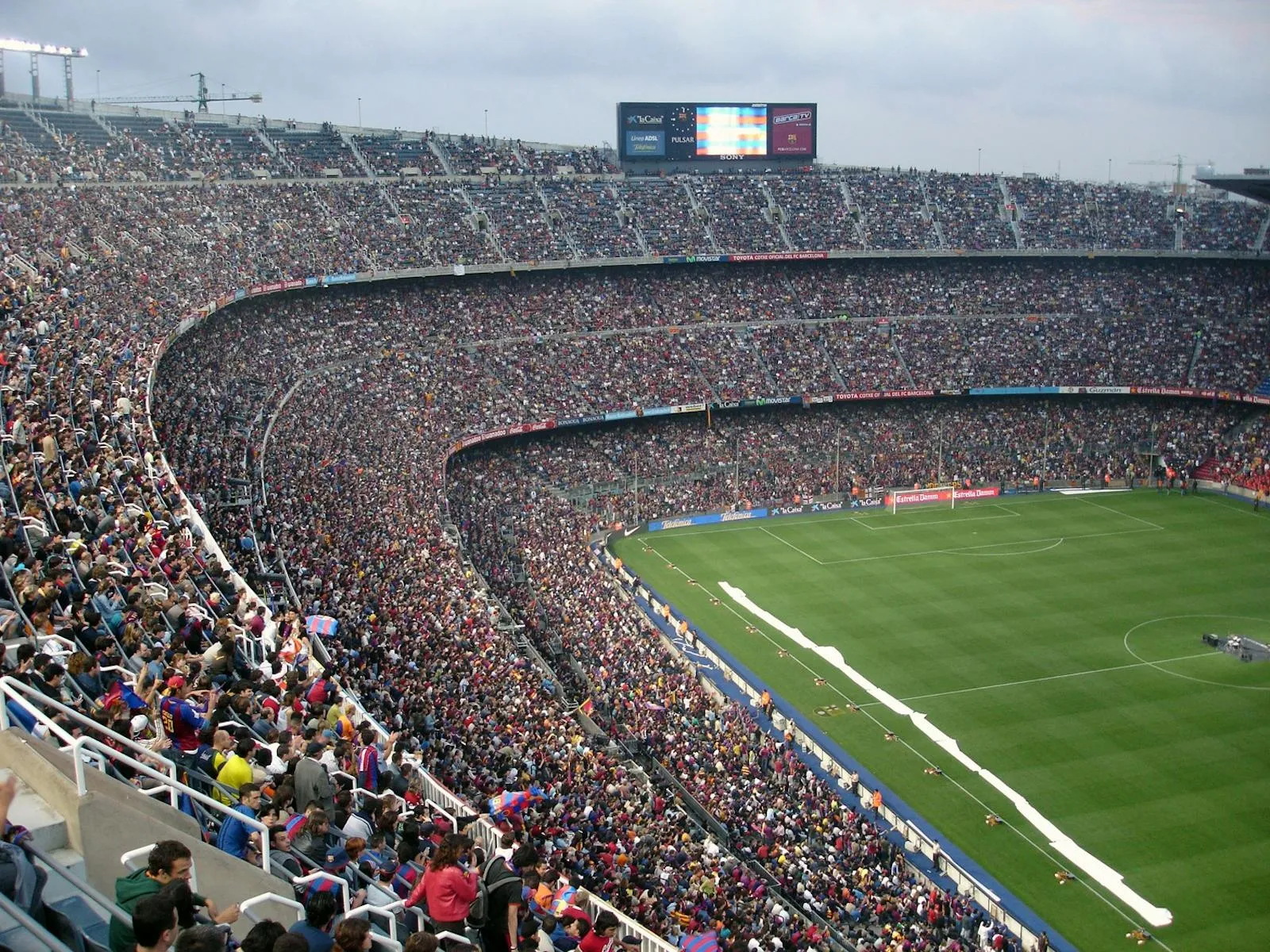 A large soccer stadium viewed from above, with tiered stands and a green playing field.