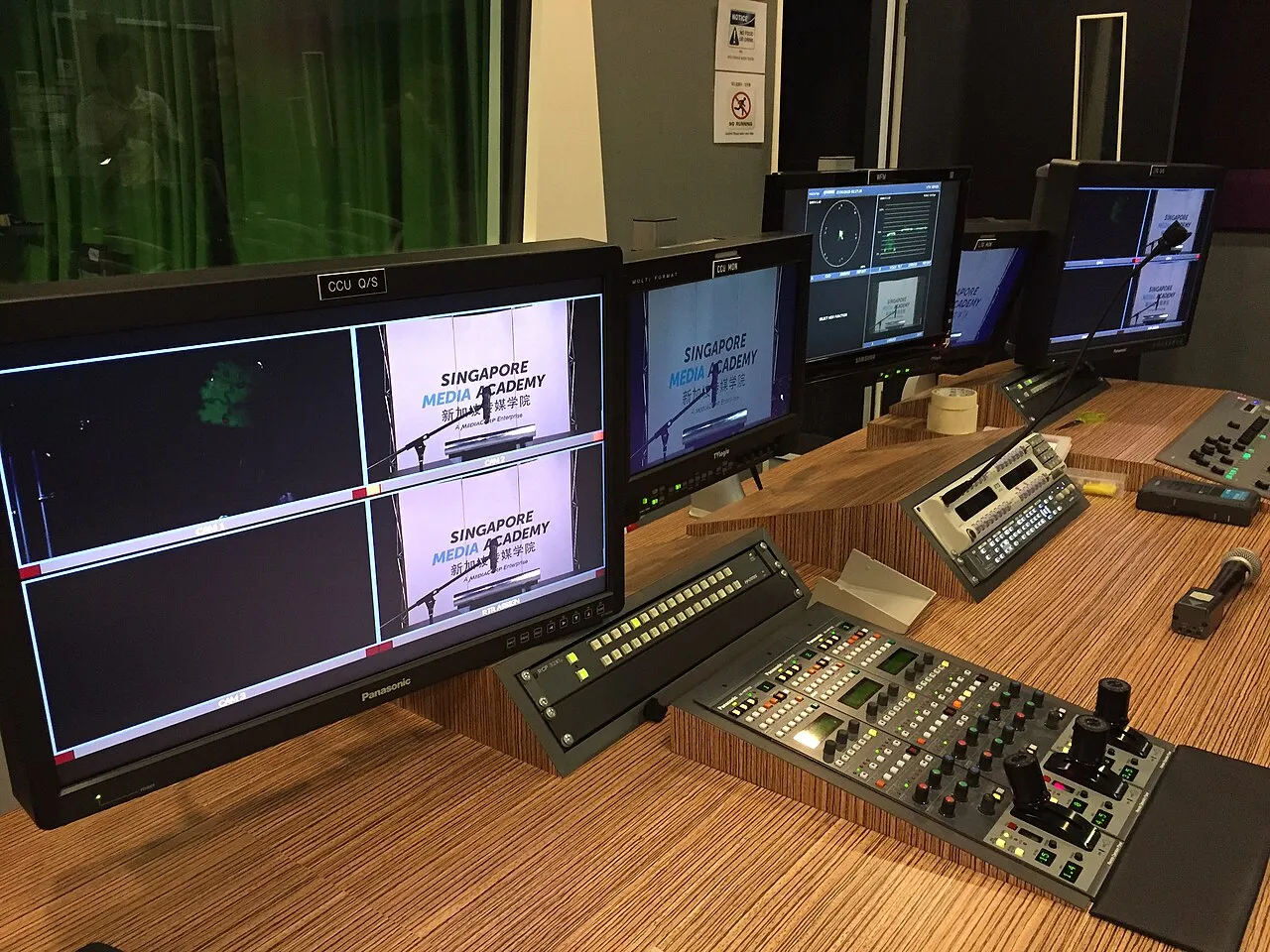 Television studio cameras and production equipment facing a set inside a media production studio.