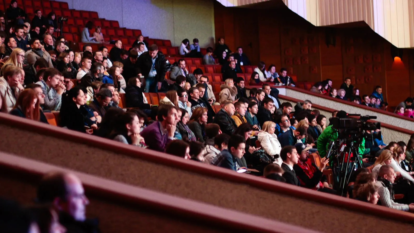 Audience members seated in a darkened movie theater watching a brightly lit screen