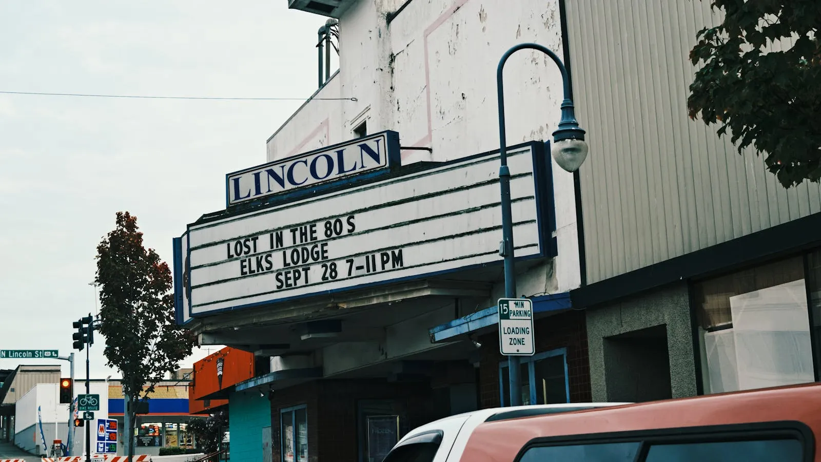 Street view of a historic movie theater with an illuminated marquee jutting over the sidewalk