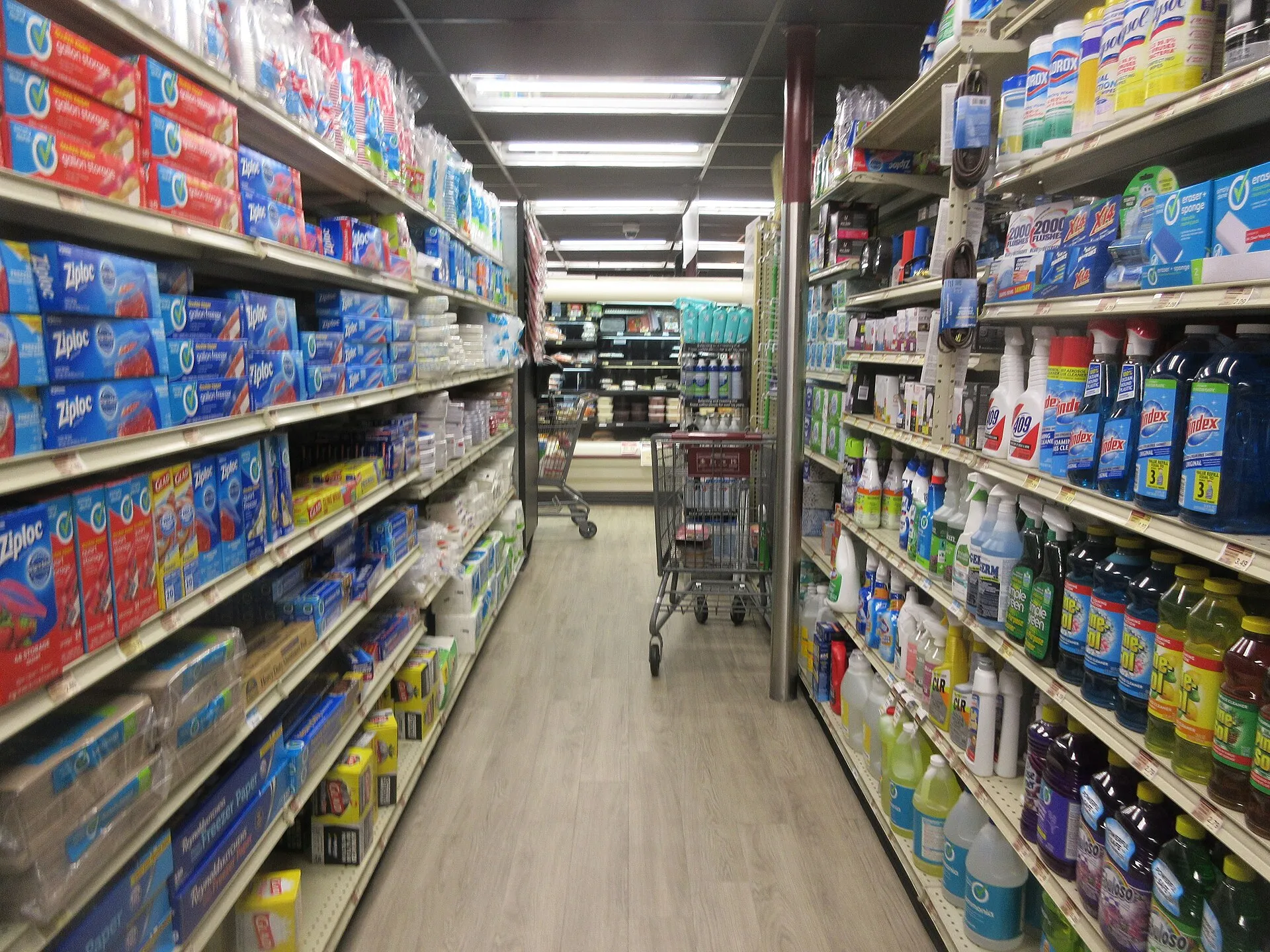 Packaged groceries line the shelves of an interior aisle at a neighborhood grocery store.