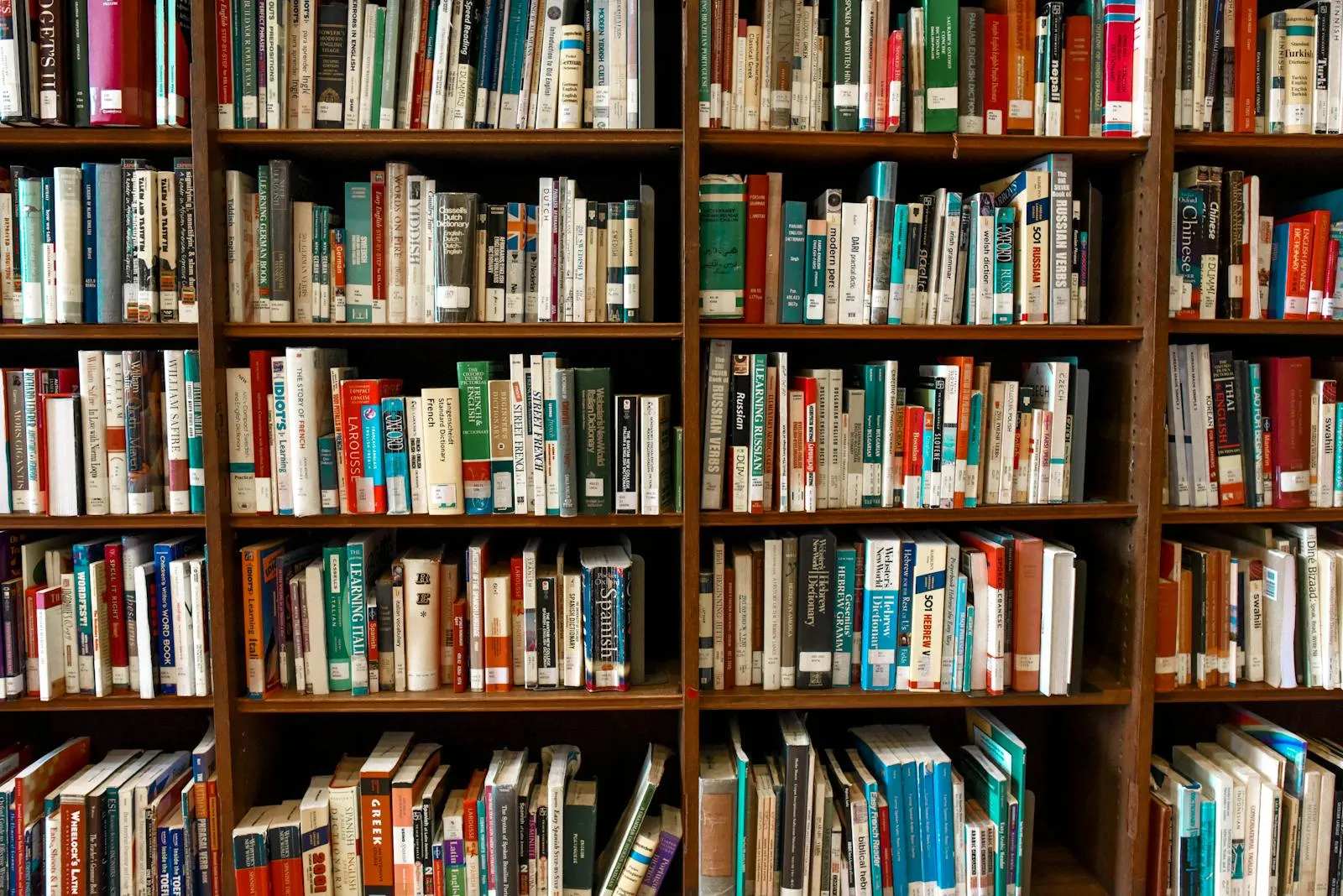 Colorful assorted books arranged on white bookshelves, with spines of varying sizes and colors.