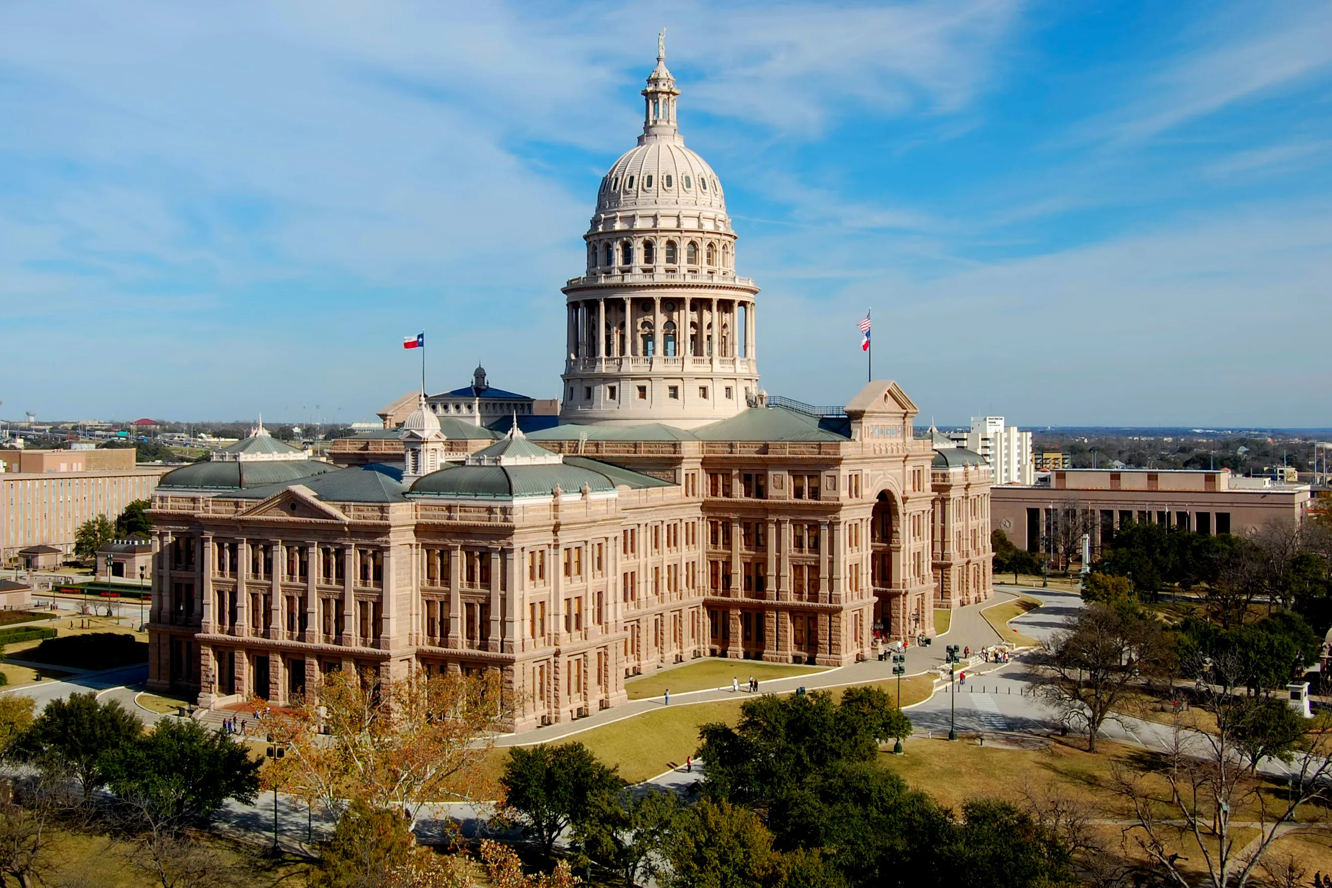 The Texas State Capitol building in Austin, with its dome and stone facade visible under a blue sky