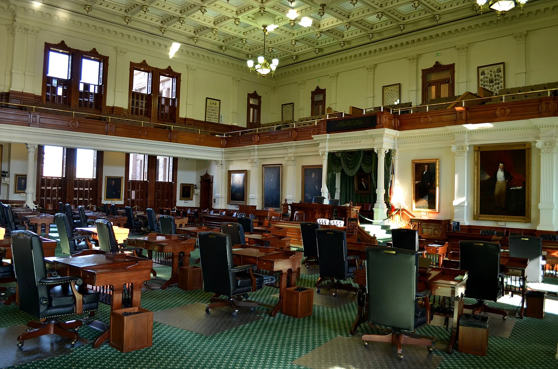 The chamber of the Texas State Senate inside the Texas State Capitol in Austin, showing ornate wooden desks arranged in a semicircle under a high ceiling with gallery seating above