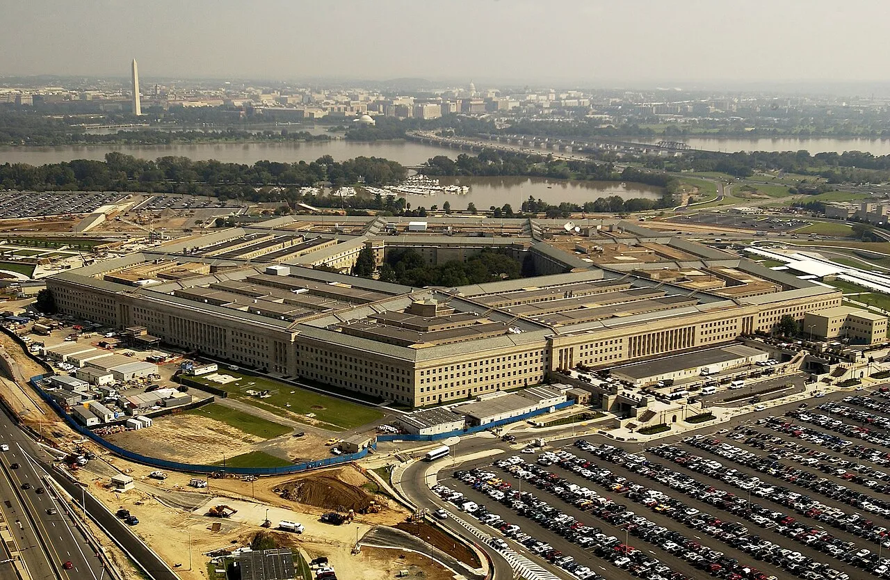 An aerial view of the five-sided Pentagon building beside the Potomac River and its parking lots.