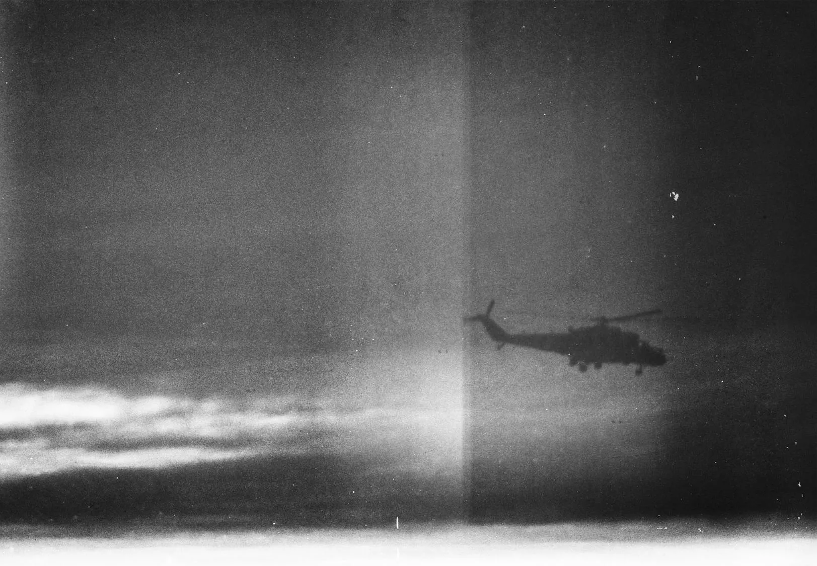 Silhouette of a military helicopter against a dramatically overcast sky