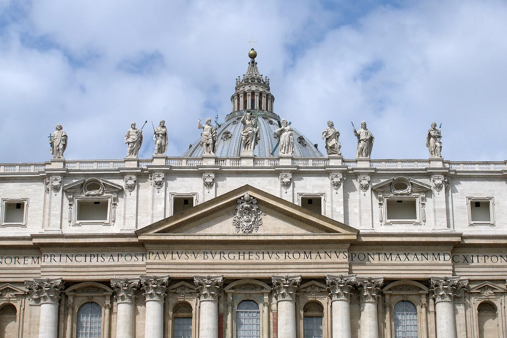 The facade of St. Peter's Basilica in Vatican City under a clear sky.