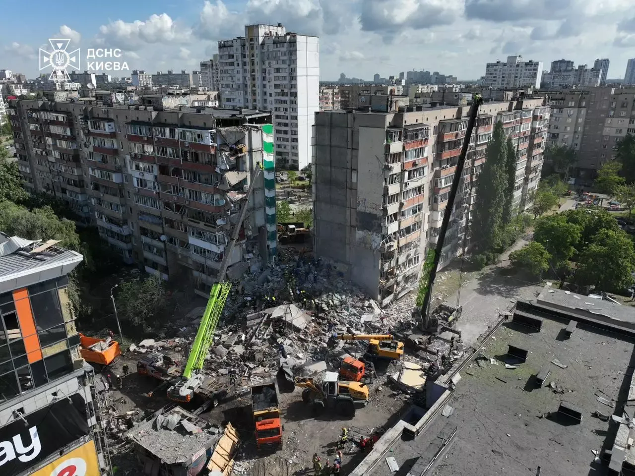 A multi-story residential building in Kyiv showing extensive structural damage from a missile strike, with collapsed floors, broken glass, and fire-blackened walls