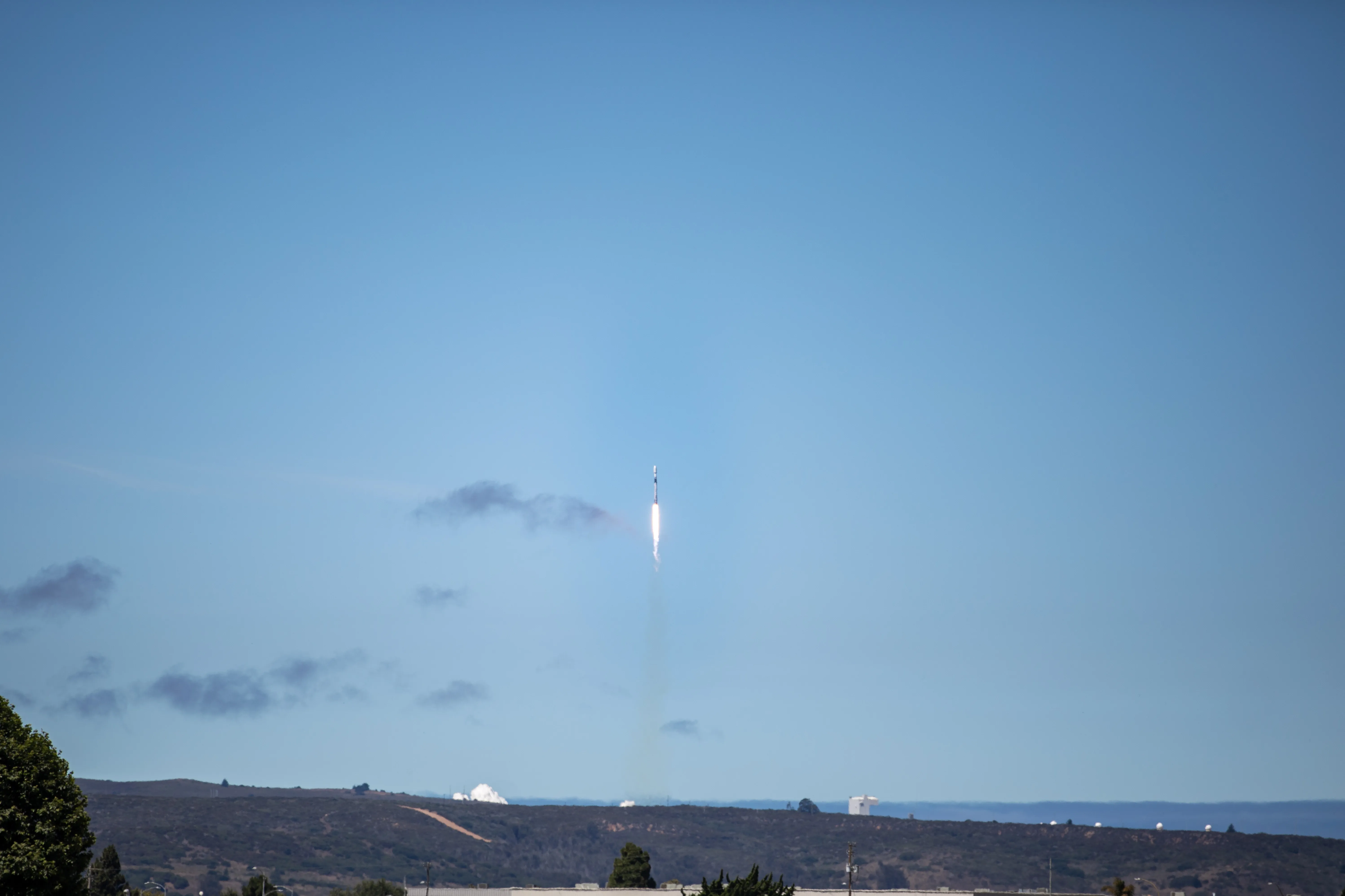 A SpaceX Falcon 9 rocket launches from Vandenberg Space Force Base in California, trailing a bright flame against a dark sky