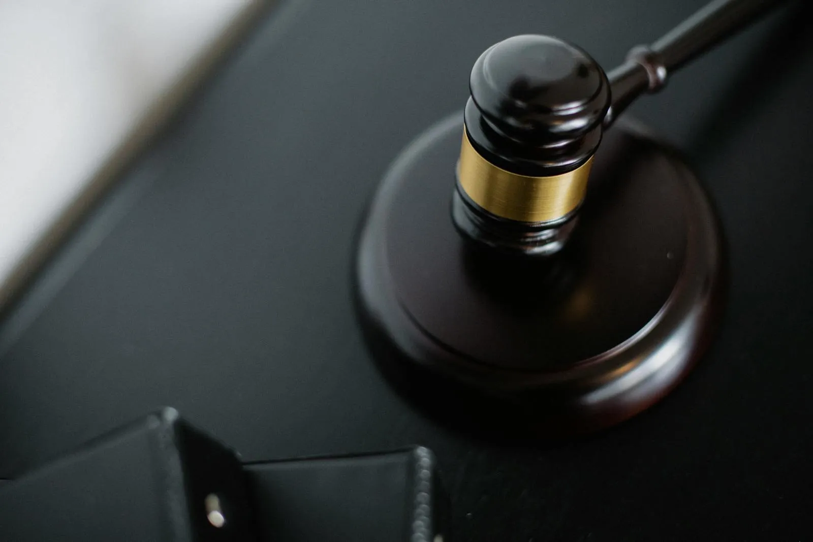 A wooden judge's gavel rests on a dark surface.