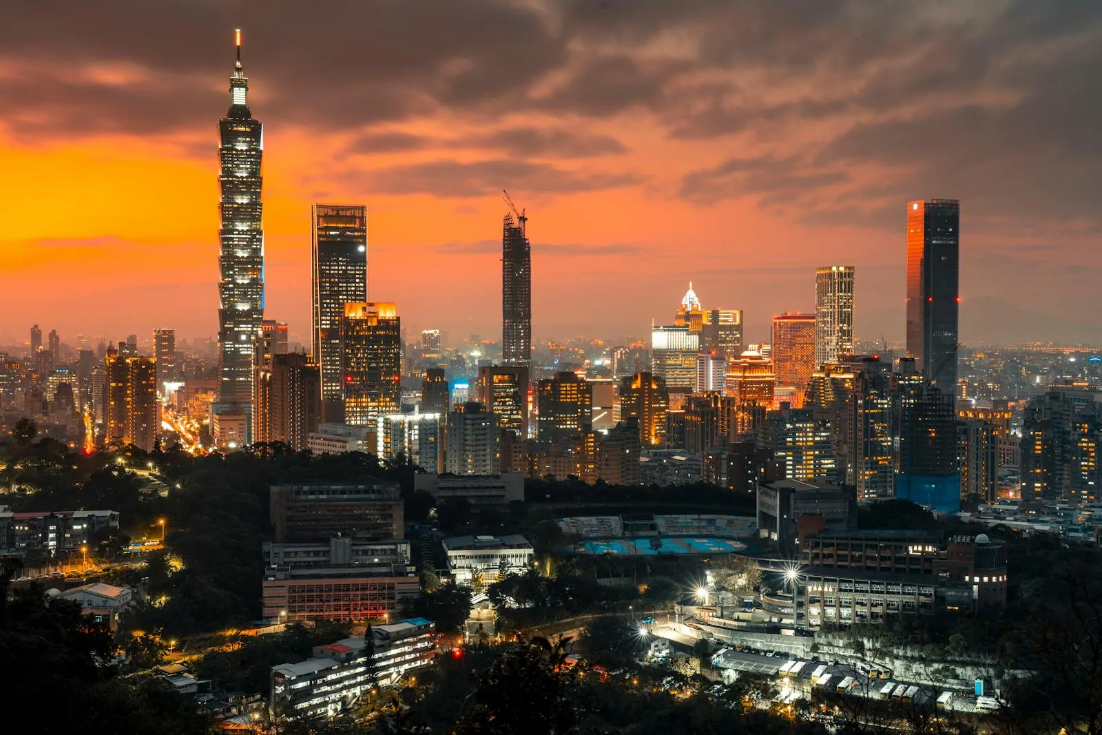 Panoramic view of Taipei's dense skyline at sunset, with Taipei 101 tower visible above the urban cityscape