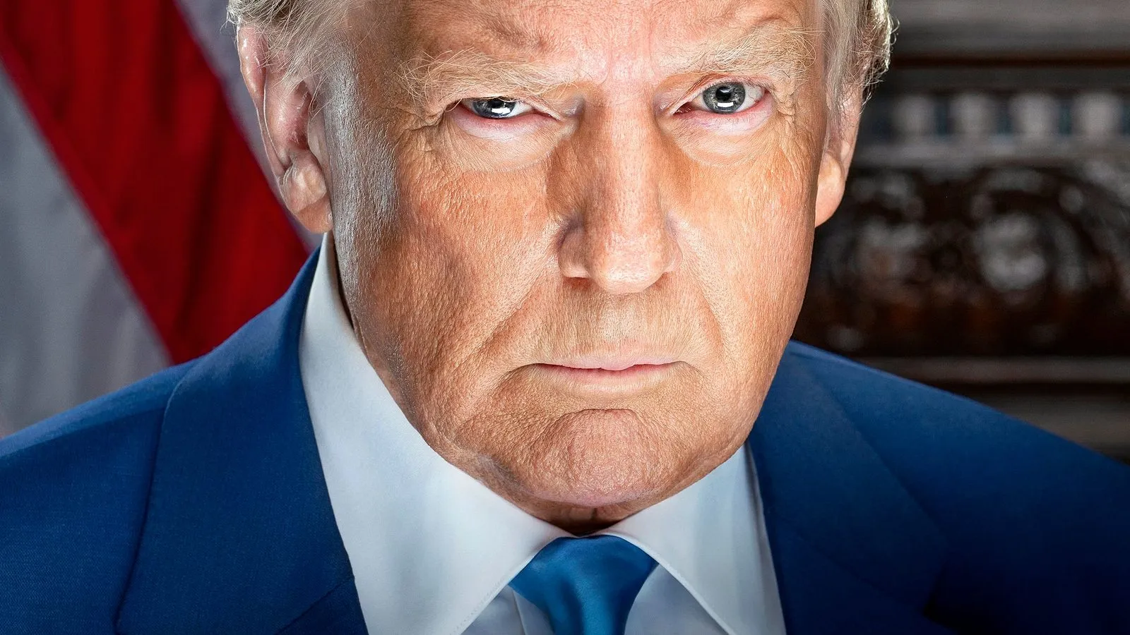 President Donald Trump in his official portrait, wearing a dark suit, red tie and an American flag lapel pin.