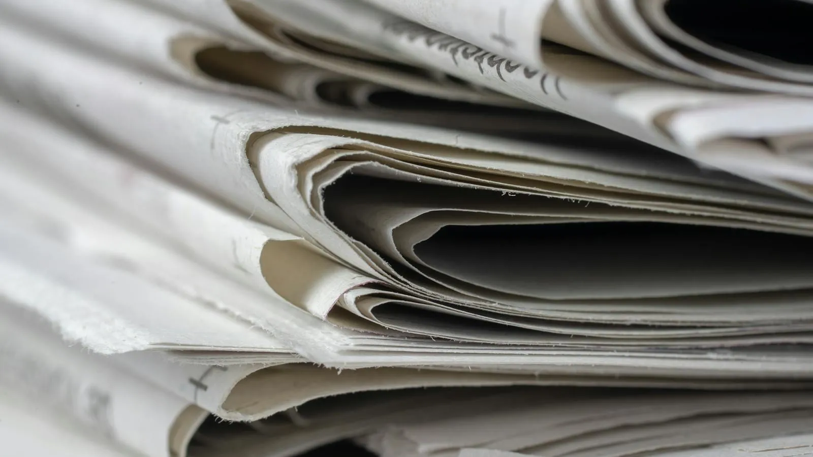 A stack of folded newspapers on a flat surface.