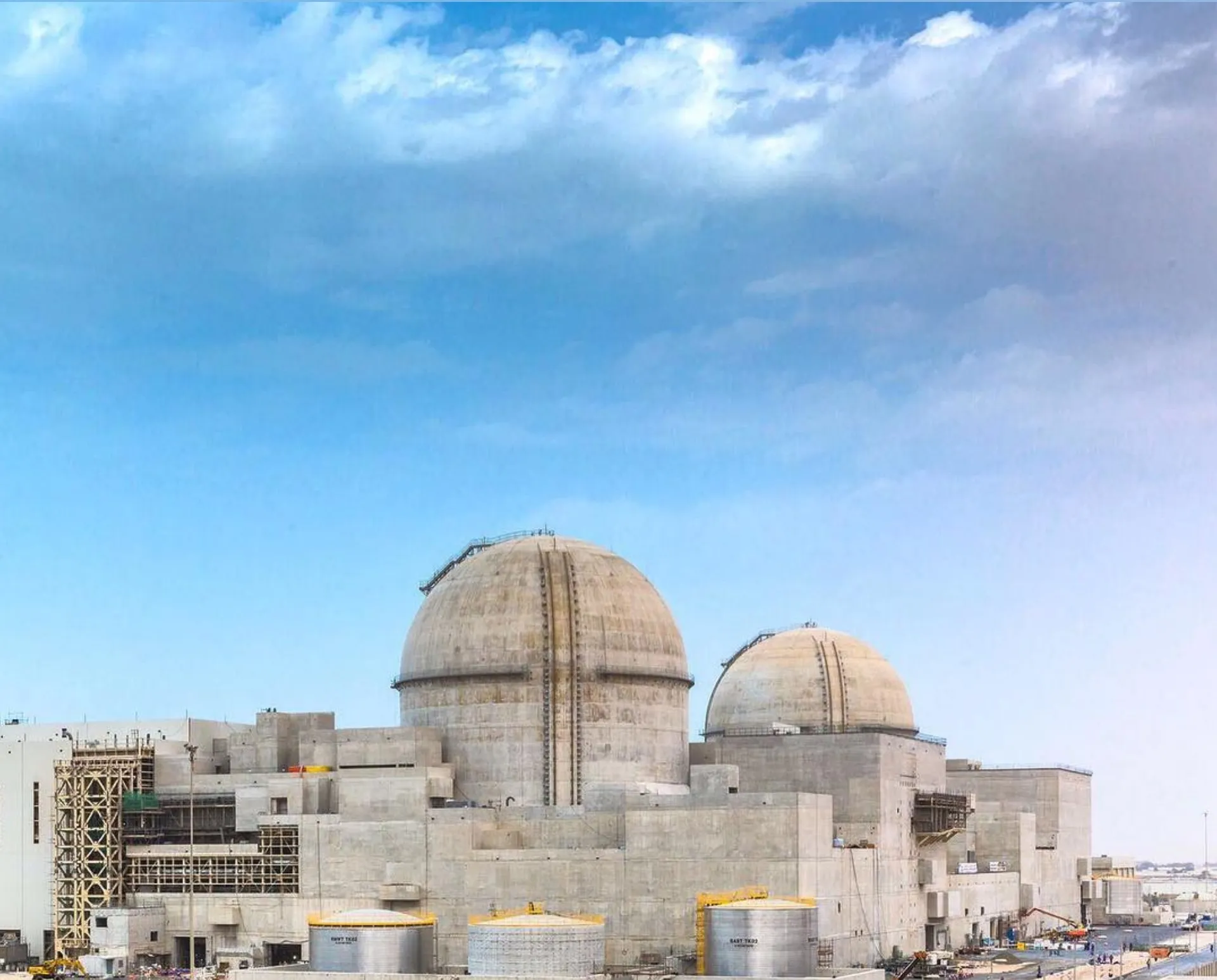 Aerial view of the Barakah nuclear power plant in Abu Dhabi, showing reactor containment domes and construction along the Persian Gulf coastline.