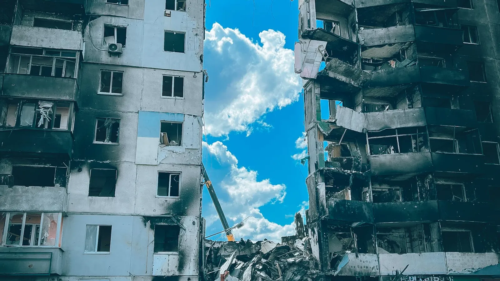 A destroyed multi-story residential building in Borodyanka, Ukraine, with blown-out walls, exposed floors, and rubble on the ground from missile damage