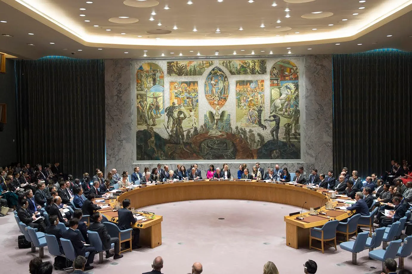 Delegates seated around the horseshoe table of the United Nations Security Council chamber during a formal meeting.