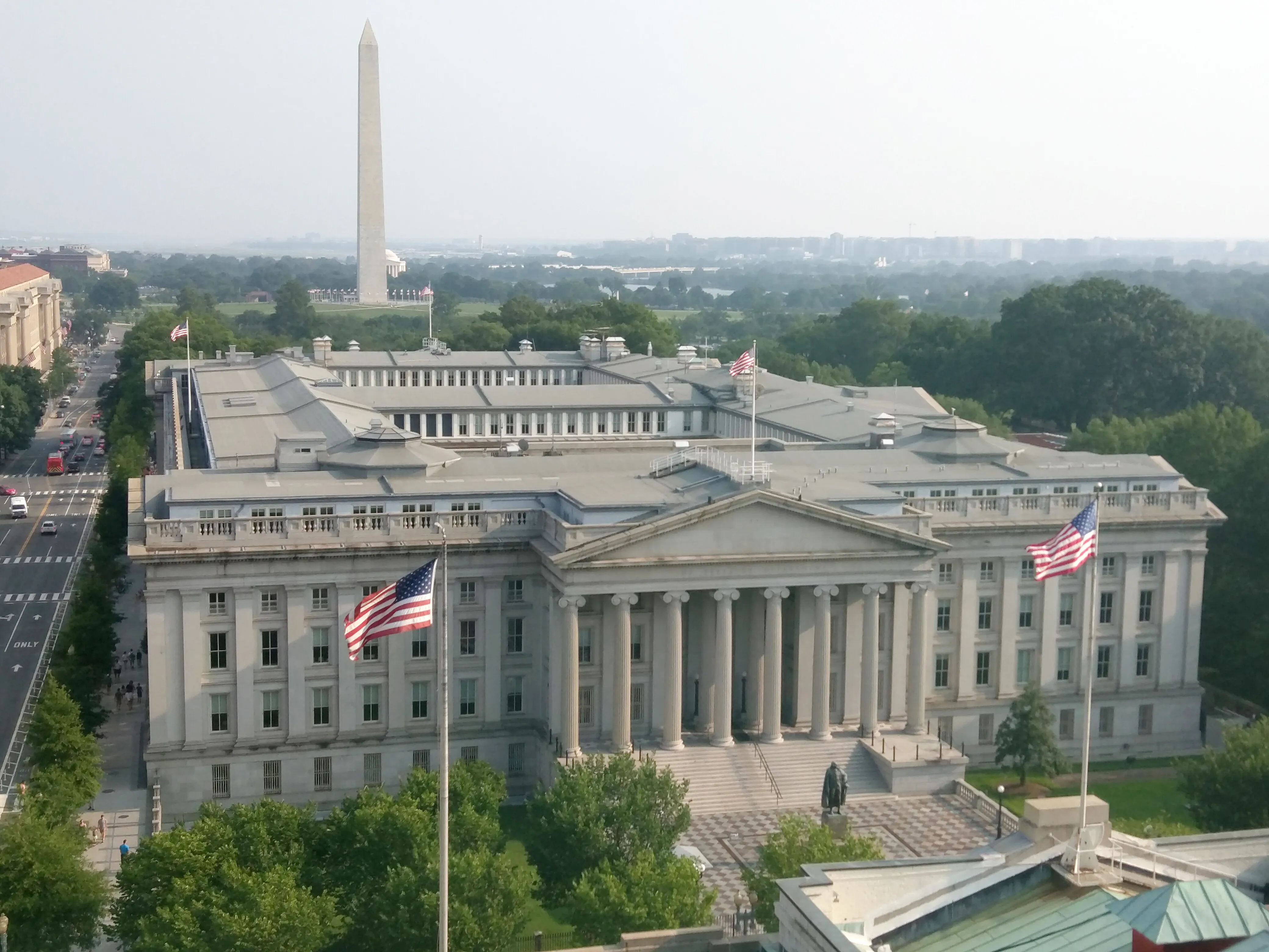The United States Treasury Building in Washington, D.C., with the Washington Monument visible in the background