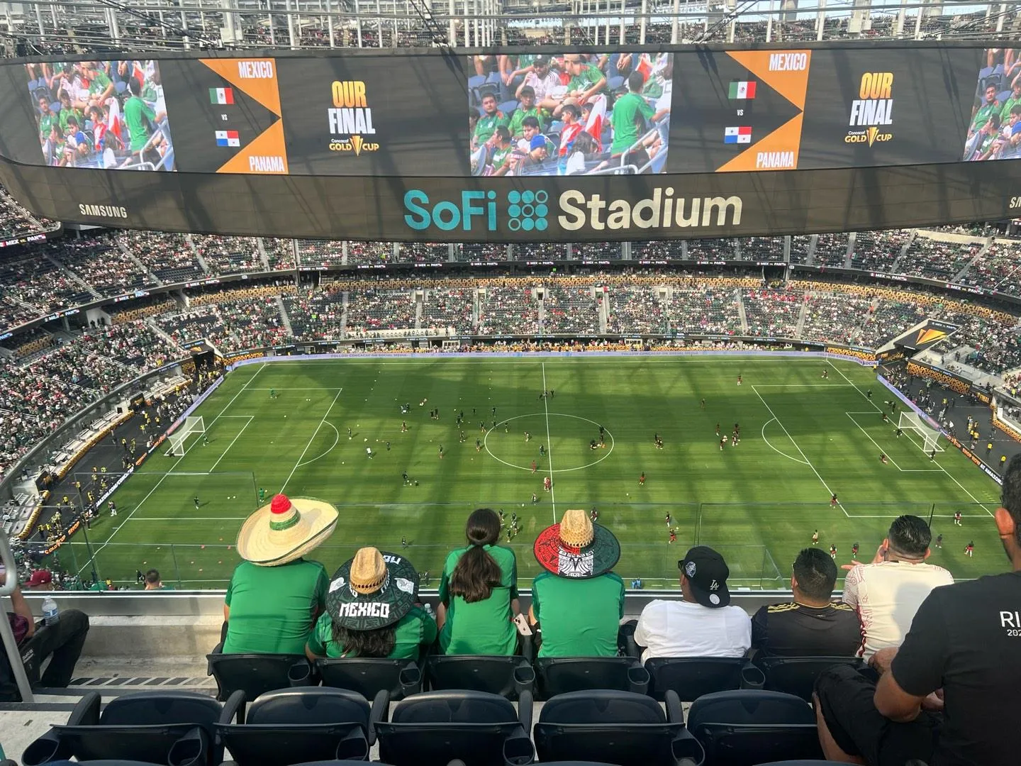 Interior of SoFi Stadium during a soccer match, a green pitch ringed by packed stands beneath the venue's roof.