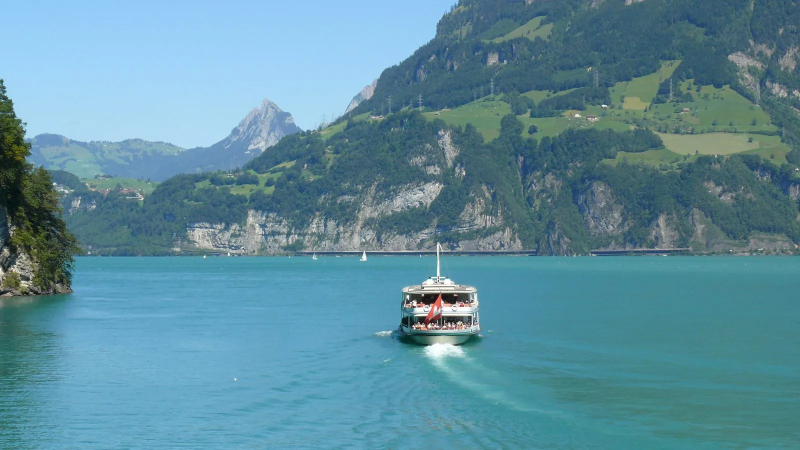 Lake Lucerne in Switzerland, a wide blue lake ringed by green mountains under a partly cloudy sky.