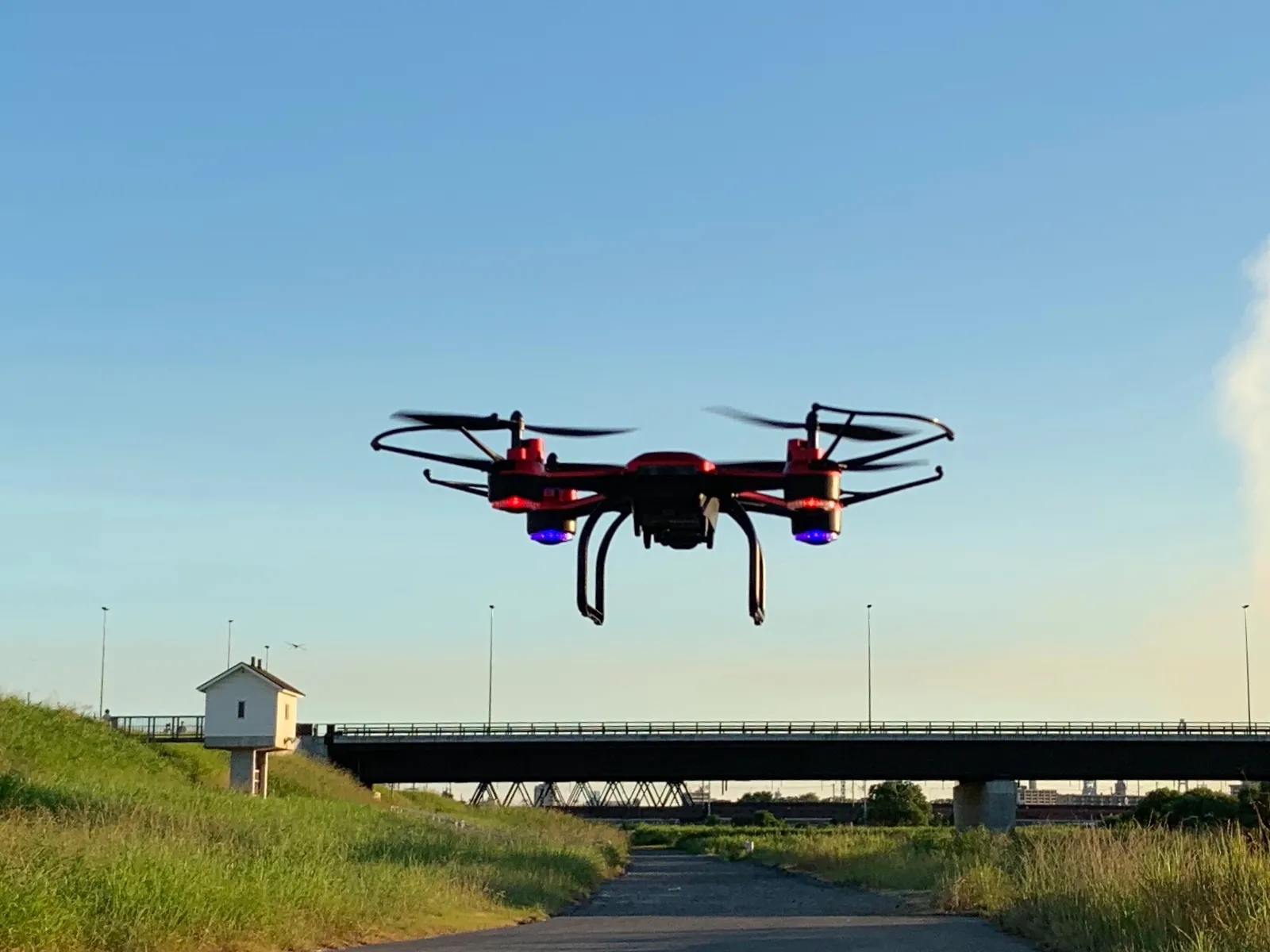 A small four-rotor consumer quadcopter drone hovers against a pale, overcast sky.