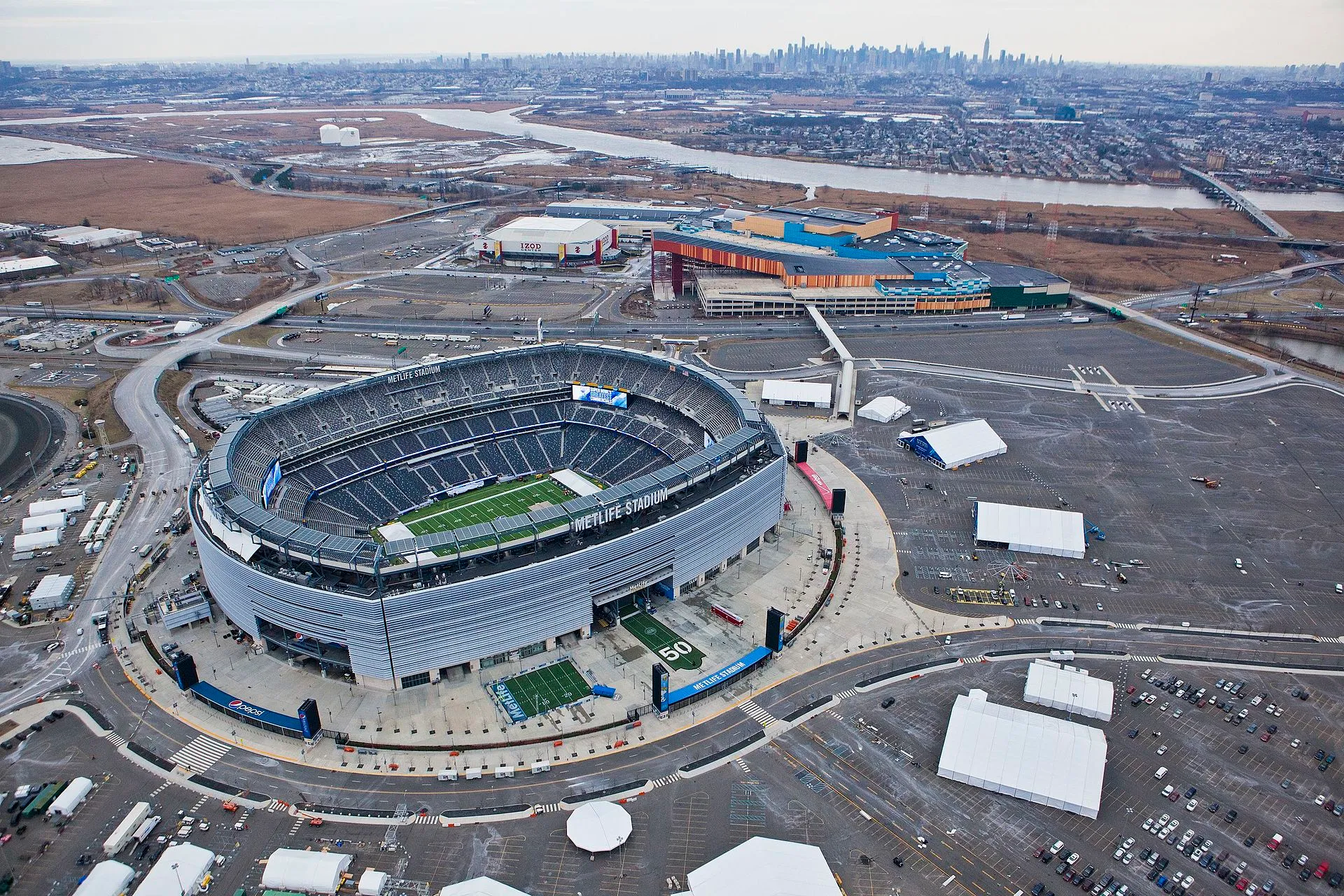 Aerial view of MetLife Stadium, a large open bowl-shaped stadium surrounded by parking lots and highways.