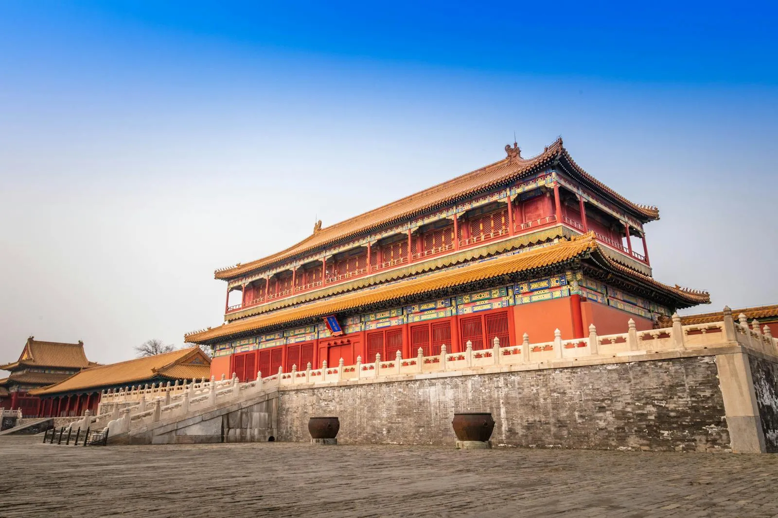 Traditional yellow-roofed pavilions and gates of the Forbidden City in Beijing viewed from the central axis, with visitors in the courtyard